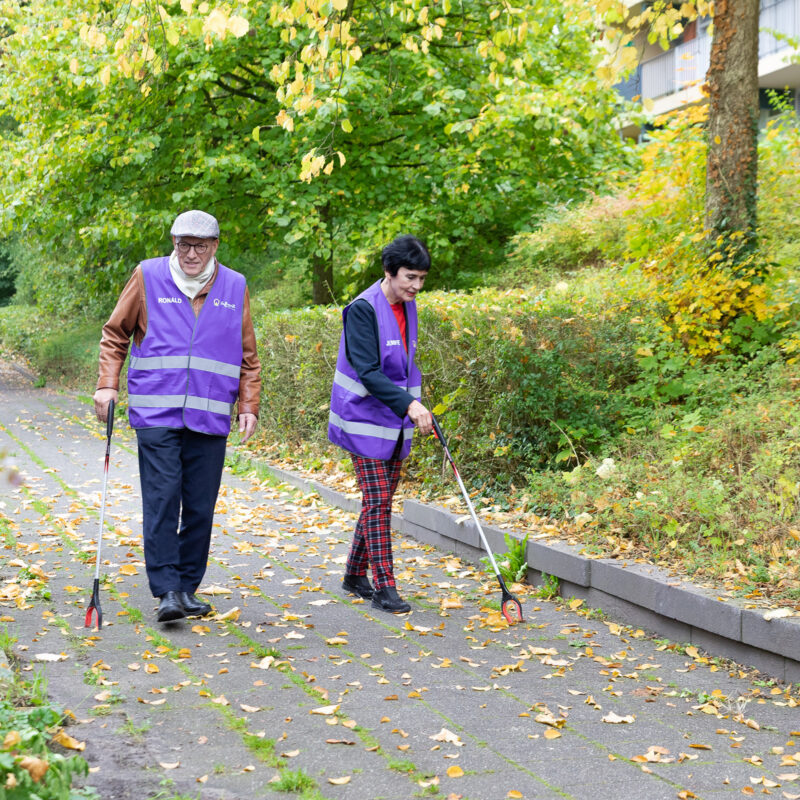 Hier zien we de vrijwilligers Ronald en Jennifer bijdragen aan een schone buurt